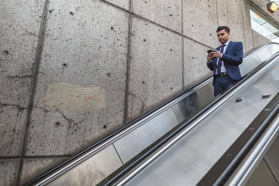man, using, smartphone, standing, escalator, people, formal, wall, infrastructure, building