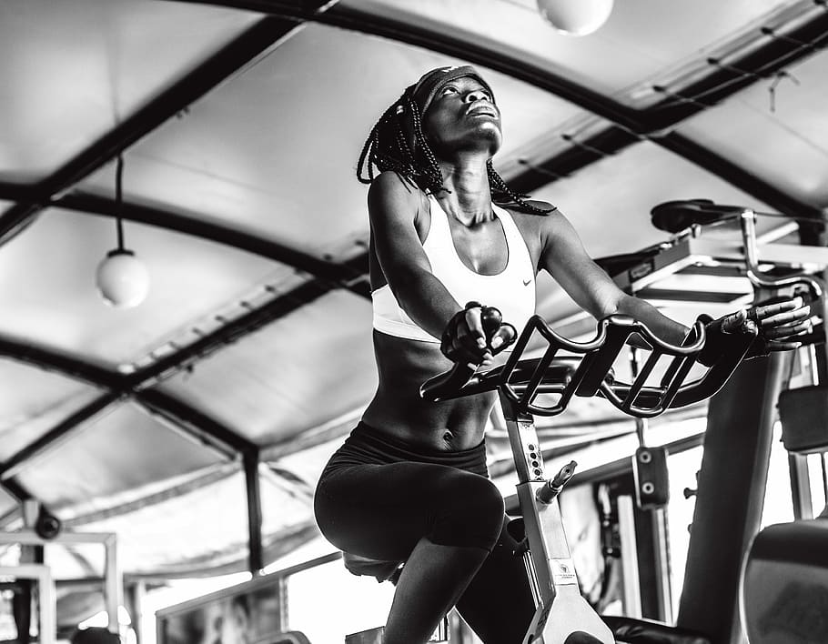 grayscale photography, woman, exercising, using, stationary, bike, people, adult, music, portrait