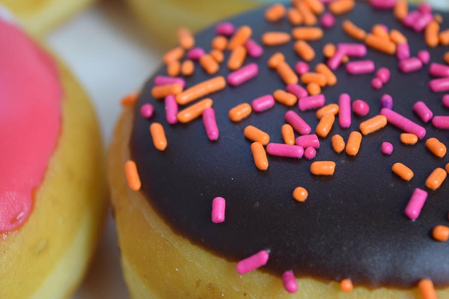 black, icing-covered donut, pink, orange, springkles, donut, baked goods, sweet, pink color, indulgence