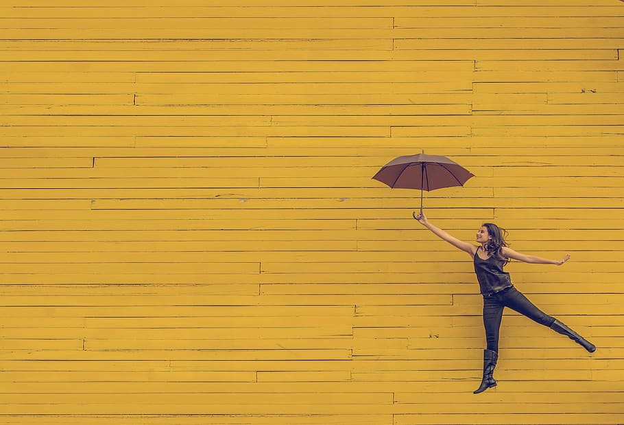 woman, holding, umbrella, jumping, yellow, background, wood, wall, people, girl
