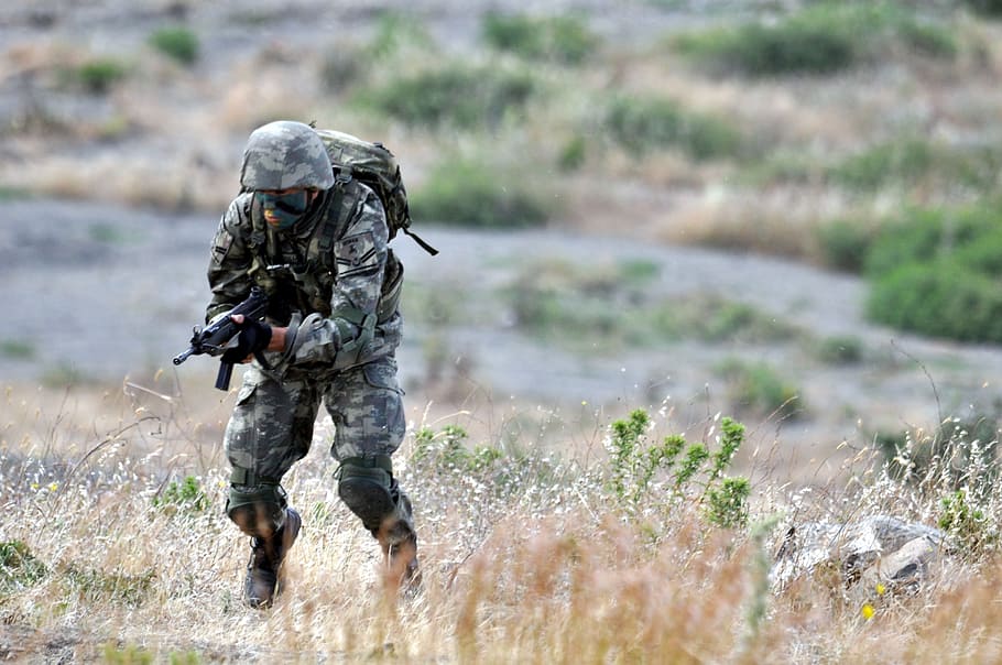 man, wearing, brown, gray, camouflage overalls, running, uphill, holding, smg, daytime