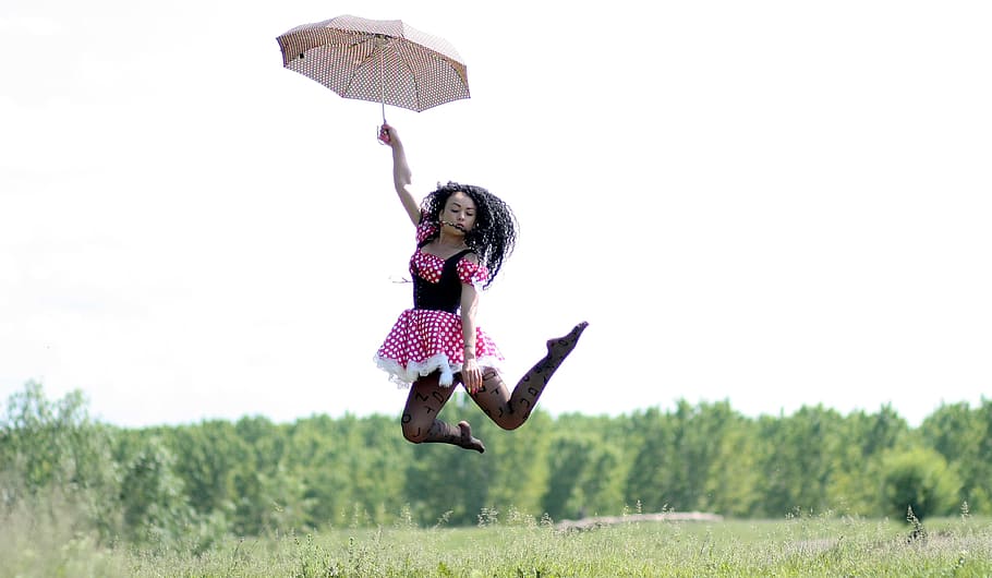 woman, holding, brown, umbrella jump, air, green, trees, background, umbrella, jump in