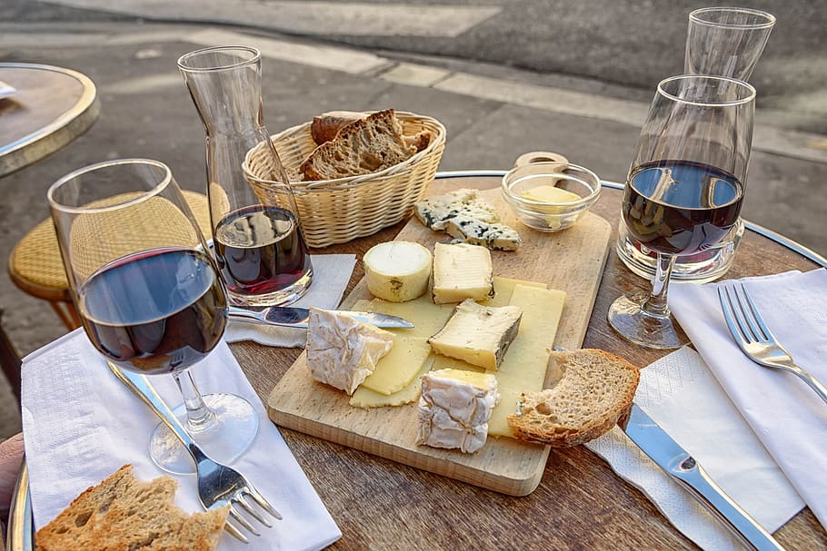 clear, short-stemmed wine glasses, sliced, breads, brown, wooden, chopping, board, wicker basket, table