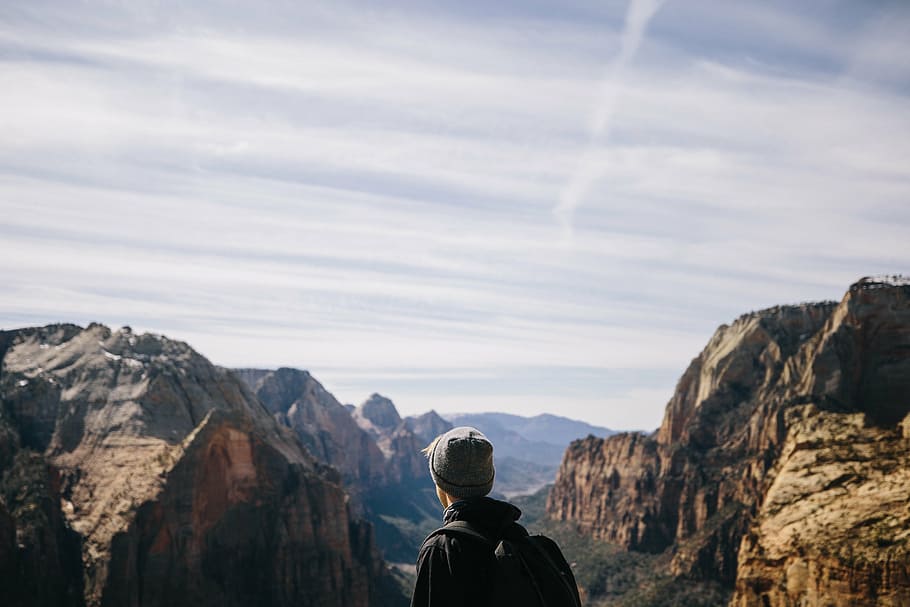 man, wearing, backpack, facing, rock formations, mountain, highland, cloud, sky, summit