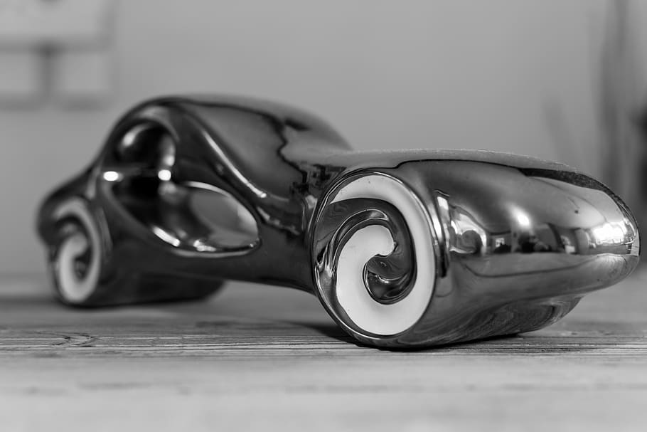 car statuette, black and white, shiny, streamline, reflection, car, aluminum, table, indoors, selective focus