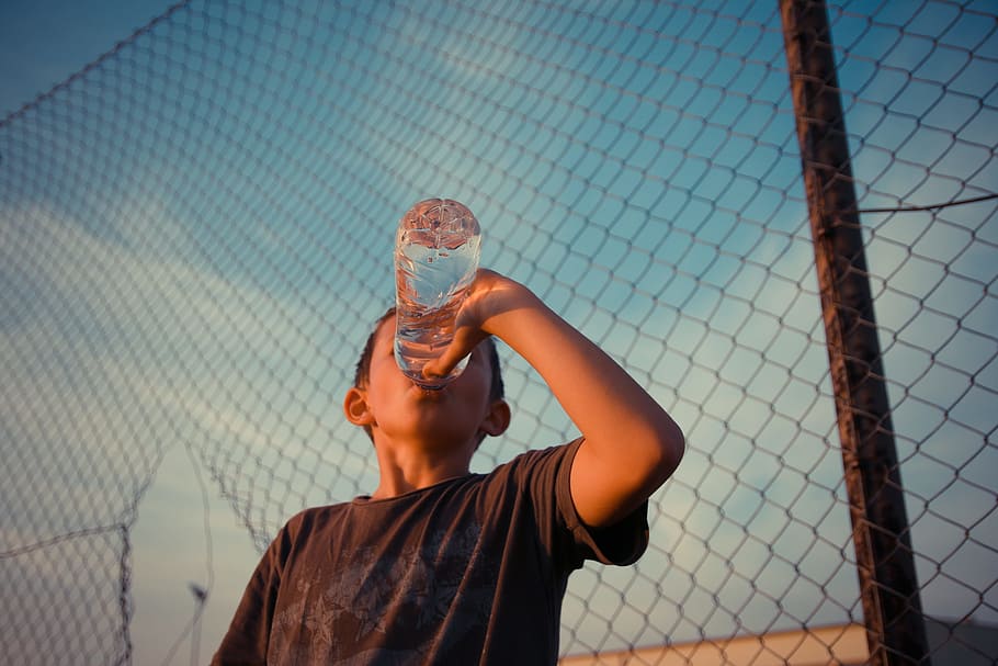 boy drinking water bottle, fence, desire, boy, water, drink, child, one person, chainlink fence, barrier