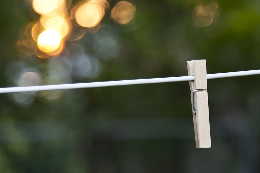 tilt shift photo, brown, wooden, clip, white, string, clothes, hanging on, bokeh, clothes pin