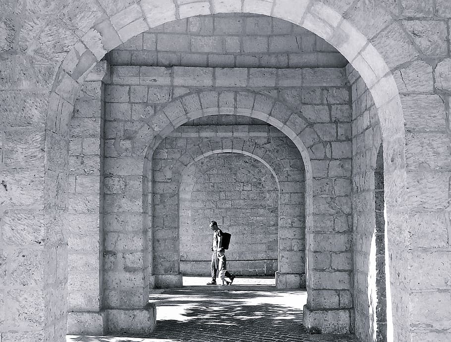 grayscale photo, person, hallway, mystery, mysterious, arch, arches, stone arch, walking, travel