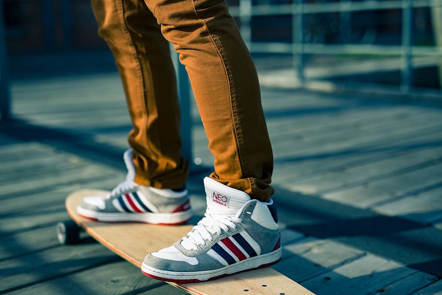 person, wearing, gray-white-and-red high-top sneakers, beige, longboard, skateboards, sports shoes, shoelaces, fun, brown pants