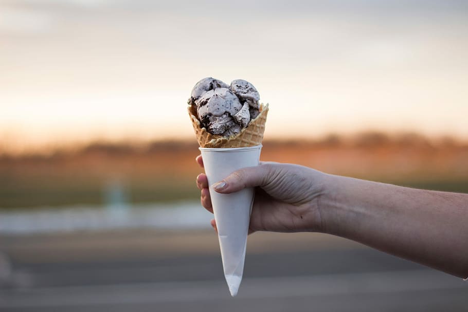 person, holding, ice cream, human Hand, dessert, close-up, human body part, outdoors, focus on foreground, food and drink