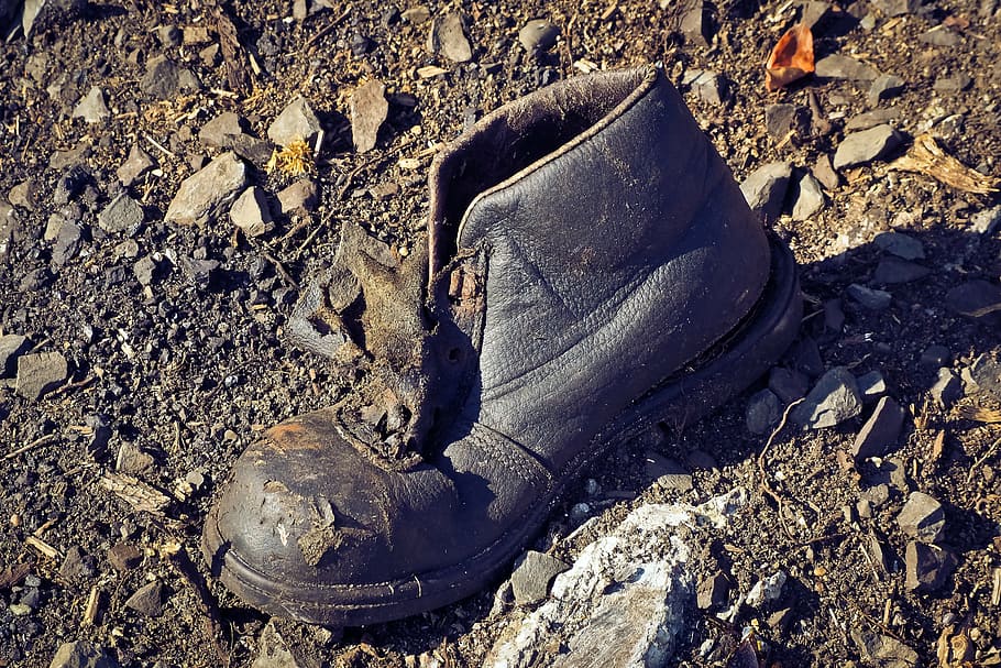 close-up photo, black, leather work boot, garbage, debris, waste, shoe, pollution, lapsed, break up