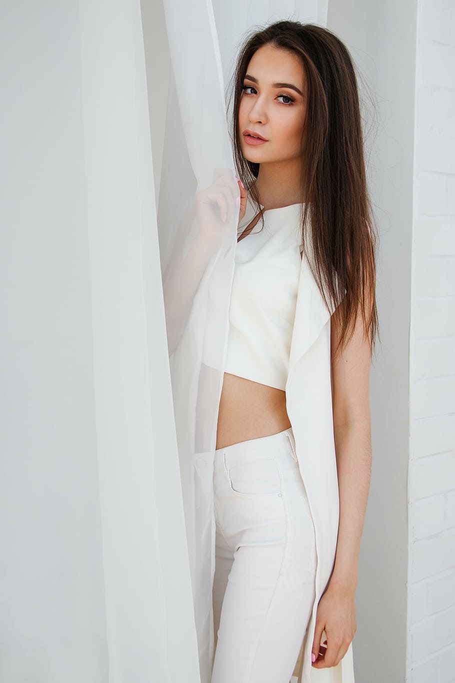 woman, wearing, white, split-neck crop, top, holding, curtain, inside, painted, room