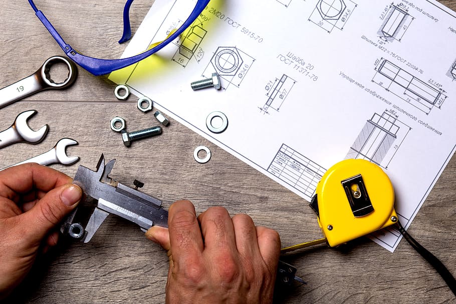 person, holding, black, metal, handheld, tool, front, sketch paper, repair, work