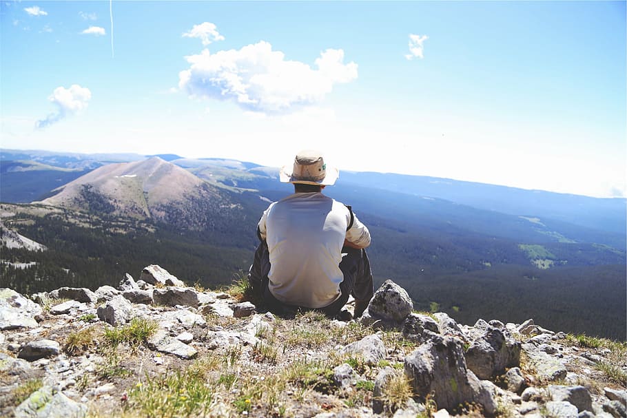 man, sitting, rock, watching, view, mountain, daytime, wearing, sun, hat