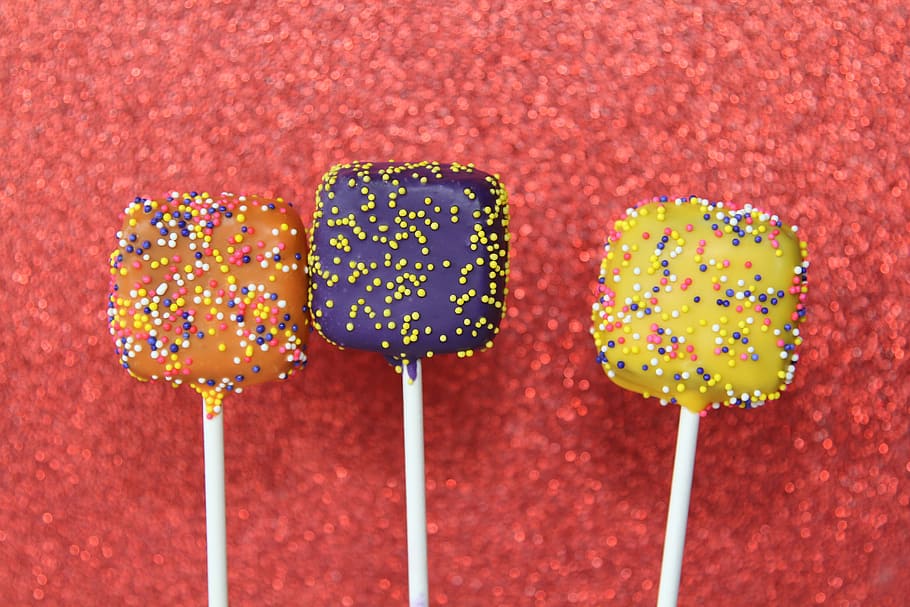 three assorted-flavor lollipops, purple, yellow, orange, cake, pops, cake pops, dessert, stick, sprinkles