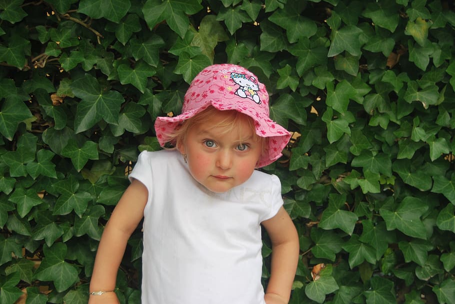 girl, wearing, pink, hello, kitty bucket hat, white, cap-sleeved blouse, standing, behind, green