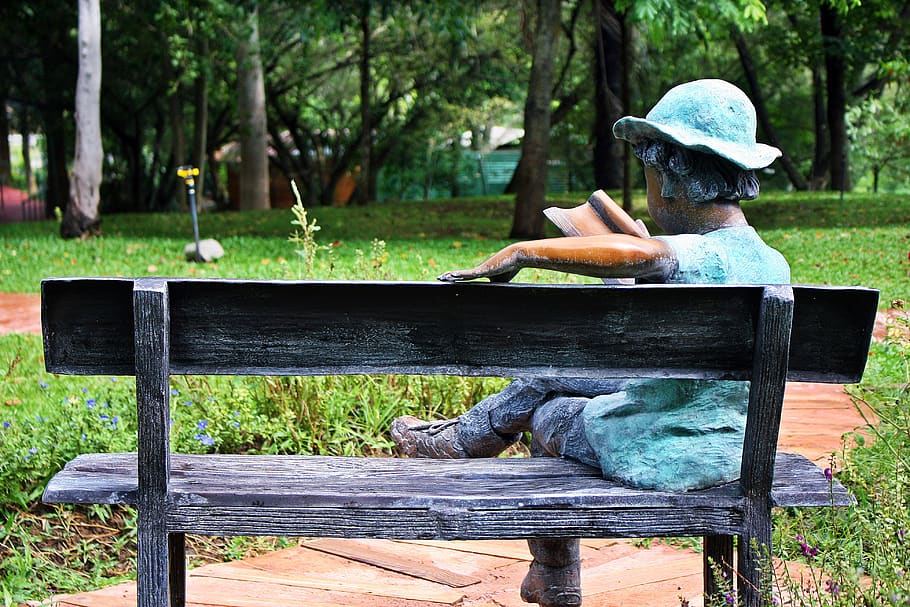 esculturas dentro del parque, el lugar de descanso de todos, estatua del niño leyendo un libro al aire libre, madera - material, árbol, planta, asiento, día, naturaleza, banco