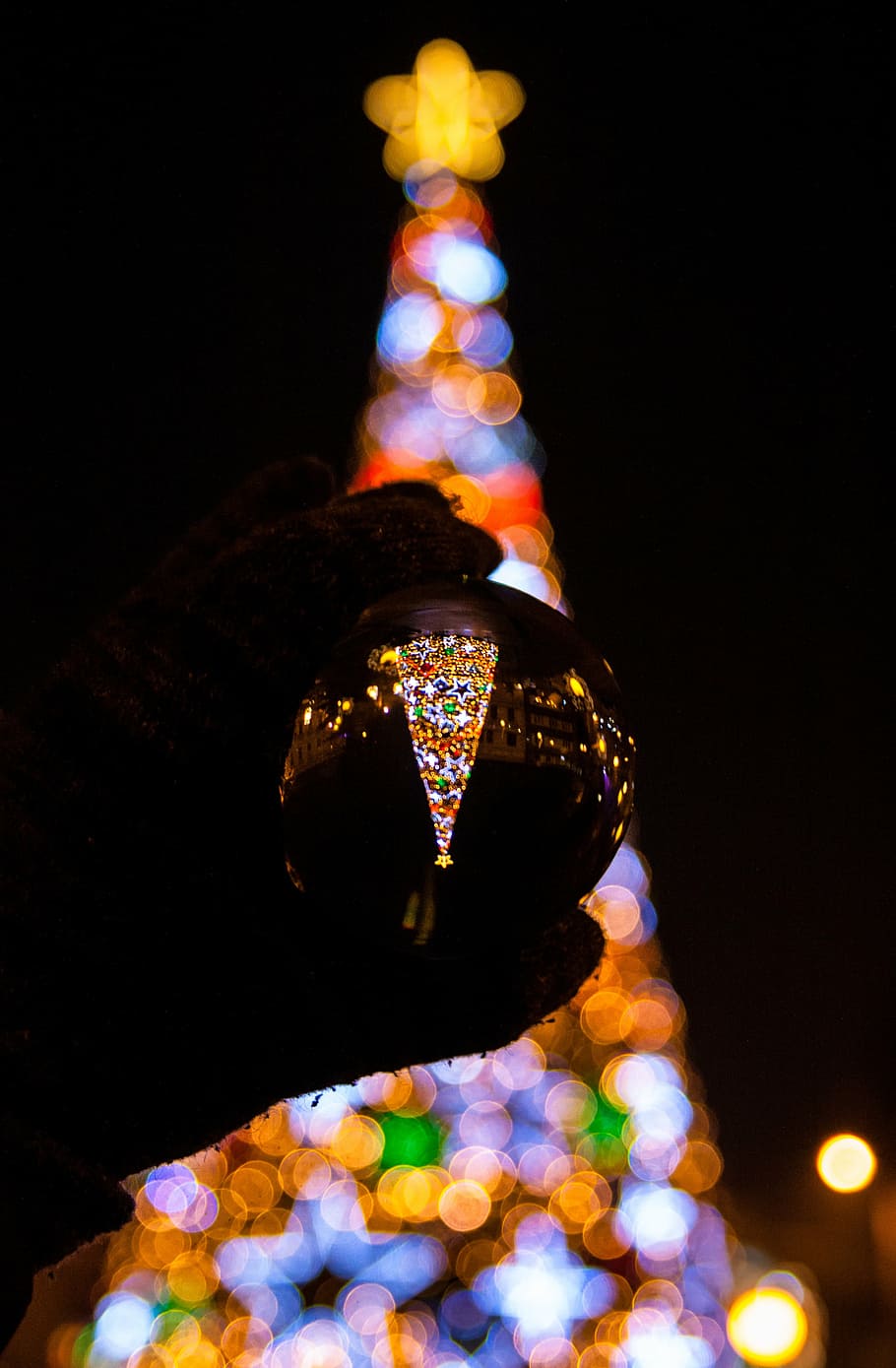 clear glass sphere, person, holding, glass, ball, nighttime, christmas, tree, lights, dark