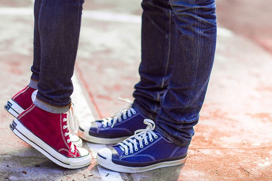 two, person, wearing, blue, denim jeans, red, high-top sneakers, standing, Converse, Couple