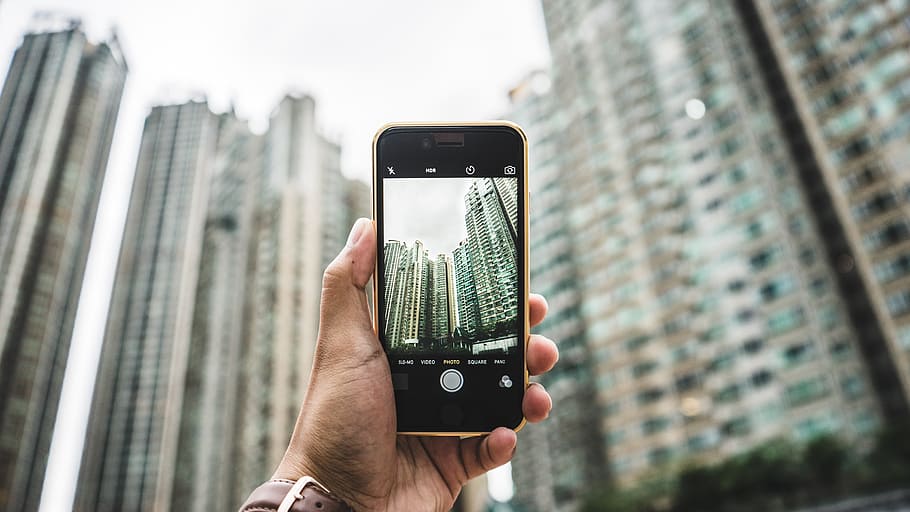 person, holding, black, iphone 7, capturing, high-rise, building, apple device, blur, buildings
