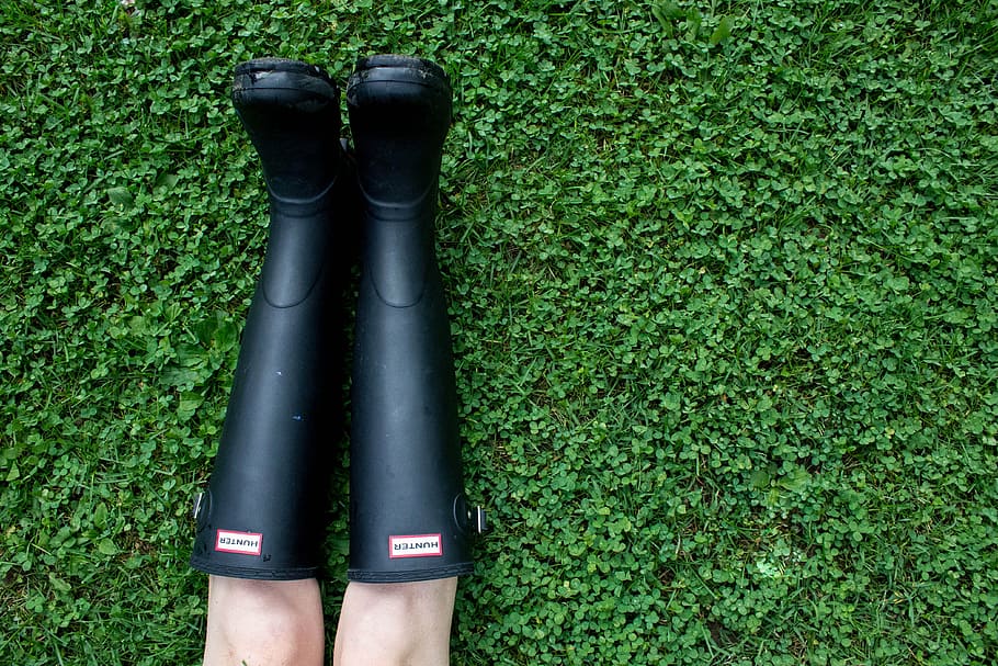 person, pair, black, hunter rain boots, green, grass, outdoor, field, leg, boots