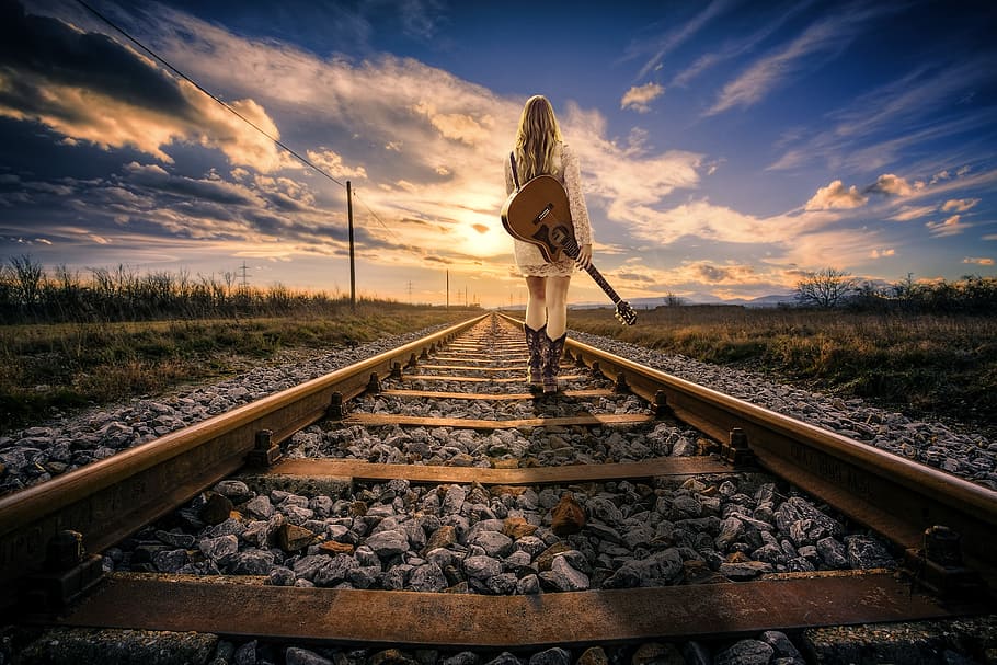 woman, carrying, acoustic, guitar, standing, railroad, daytime, railway line, railway, rail