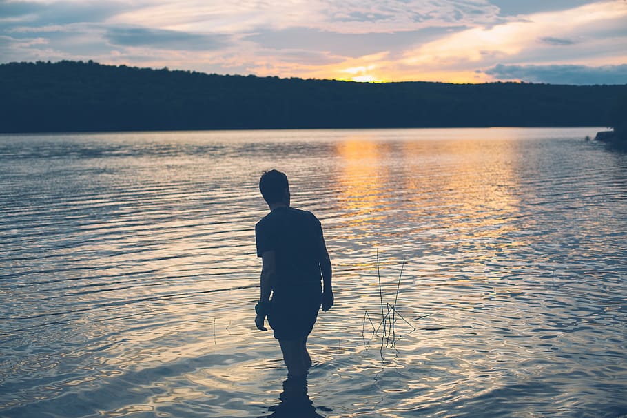 silhouette photo, man, standing, body, water, silhouette, person, distance, hill, golden