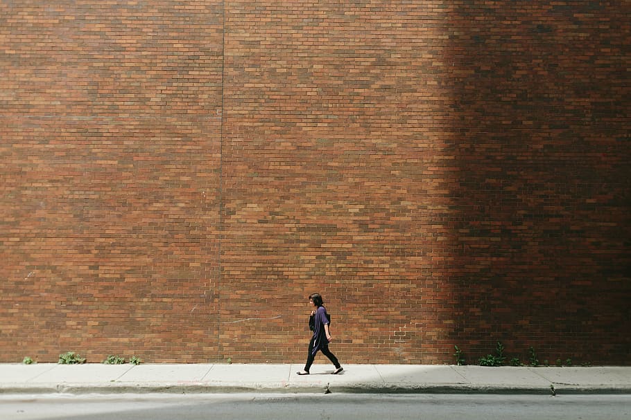 woman, walking, street, along, red, brick wall, girl, pavement, person, wall