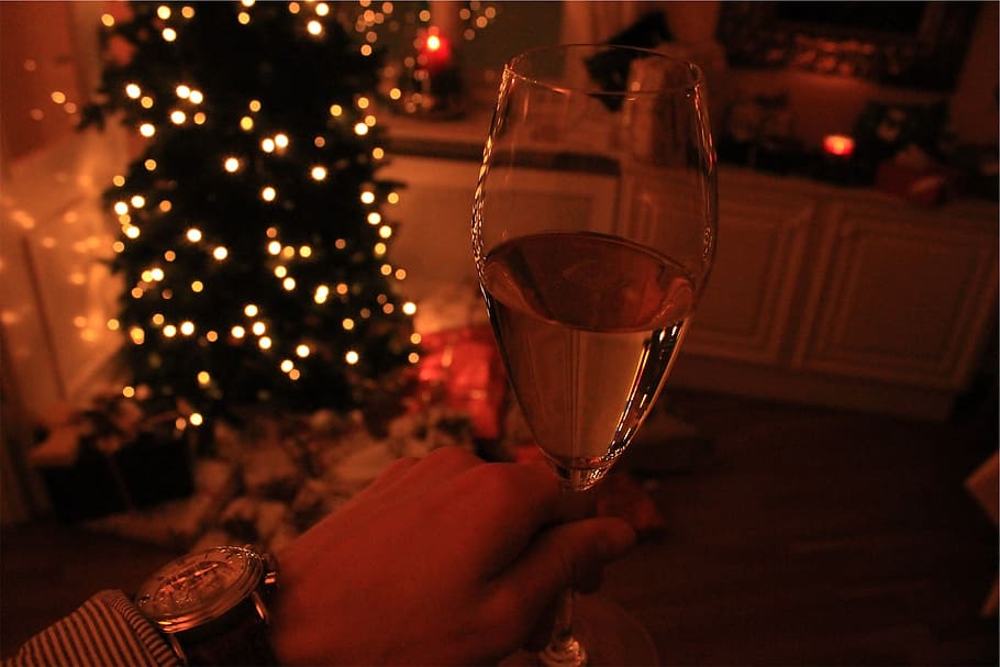 person, holding, half-filled, wine glass, inside, dark, room, wine, glass, christmas tree