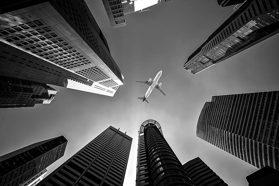 low, angle, grayscale photo, airplane, tall, buildings, the air, airline, architecture, background