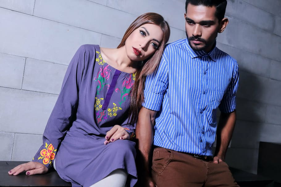 man, blue, pinstriped dress shirt, standing, woman, purple, floral, sitting, black, wooden