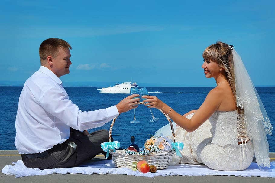 wedding couple, holding, wine glasses, sitting, seashore, blue, sky, daytime, wedding, romance