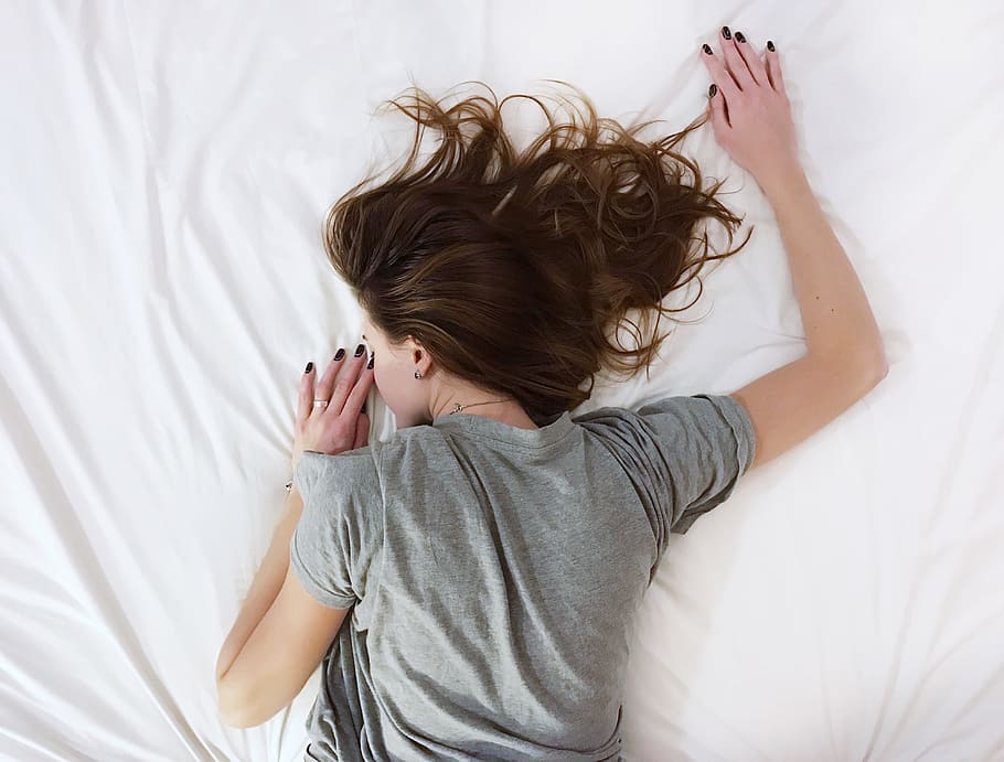 woman, wearing, gray, t-shirt, sleeping, white, bed comforter, sheet, bed, room