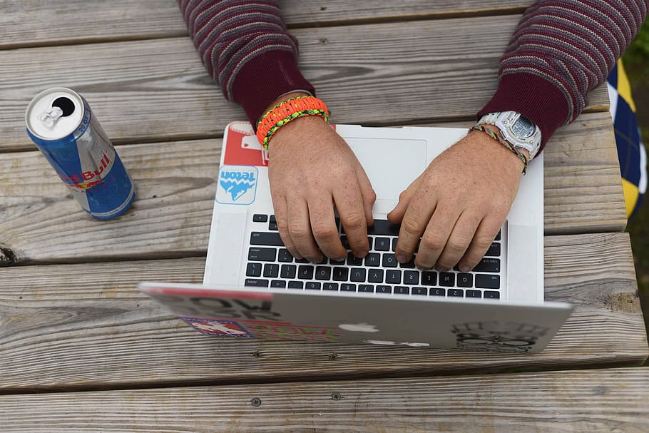 pessoa, usando, MacBook de prata, Macbook, branco, ao lado, vermelho, touro, lata, mão