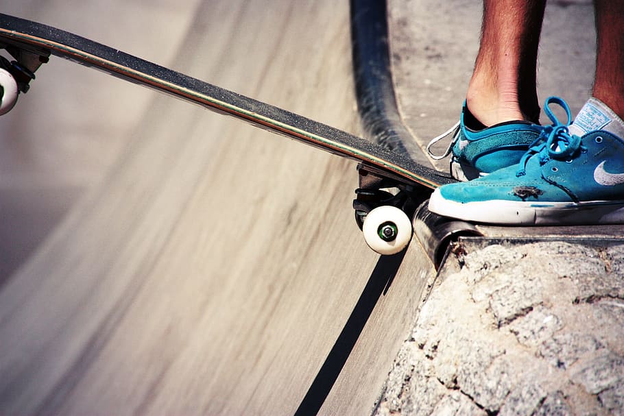 close-up photography, person, wearing, blue, nike low-top sneakers, stepping, black, skateboard, ramp, daytime