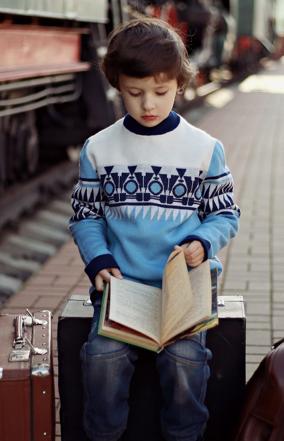 boy, wearing, multicolored, sweater reading, holding, book, lap, train, sweater, kid