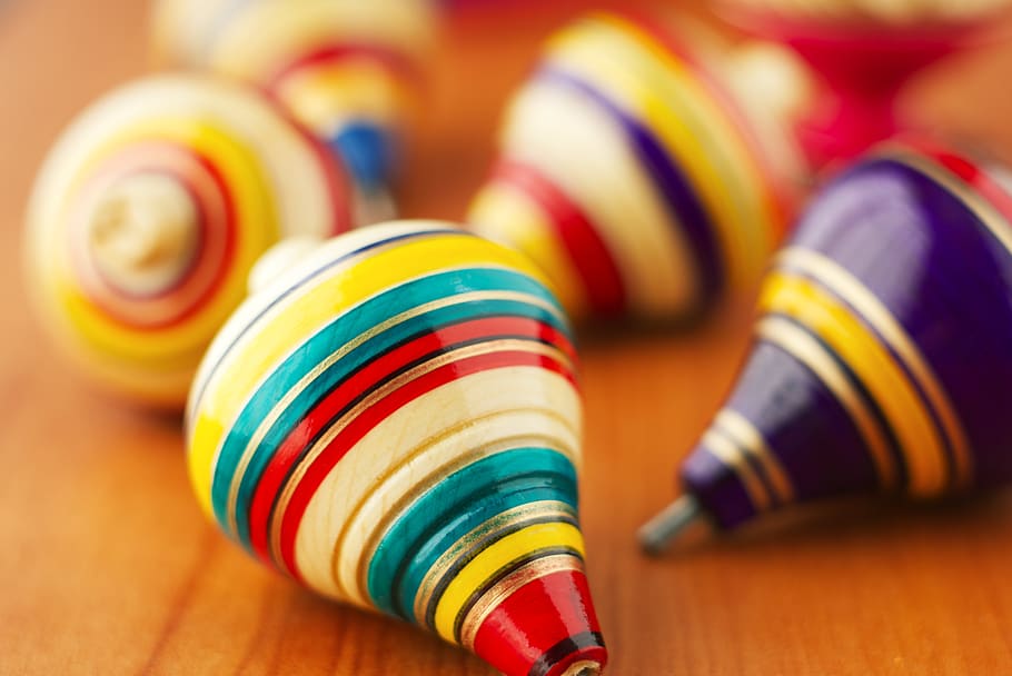 toys, wood, spinning tops, toy, traditional, multi colored, close-up, selective focus, table, indoors