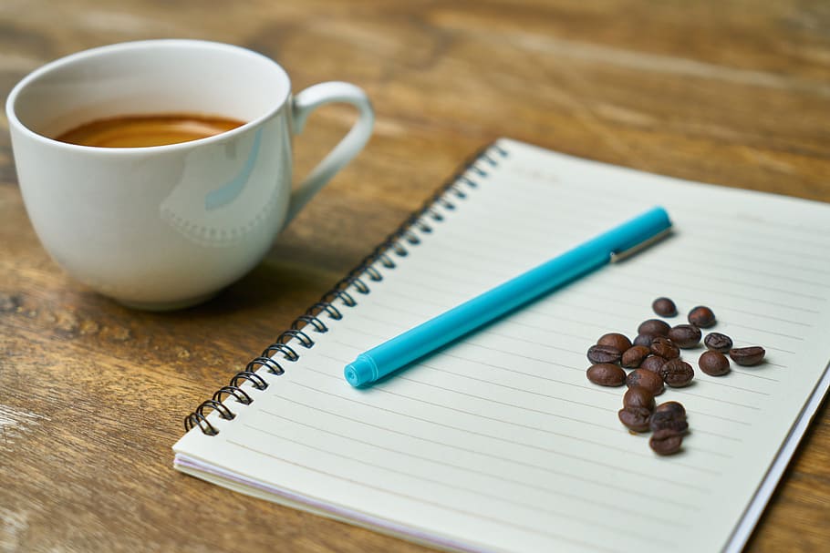 teal ball-point pen, white, notebook, coffee bean, coffee, cup, beverage, espresso, cappuccino, food photo