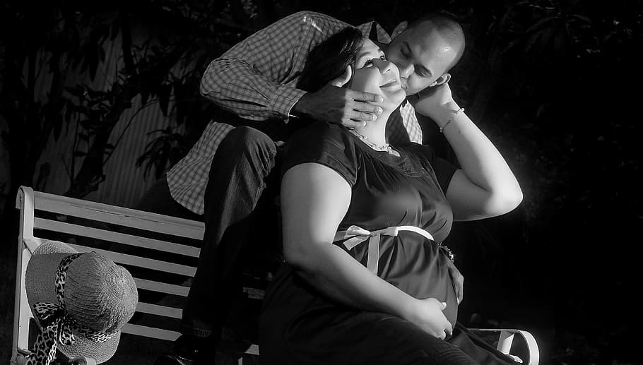 grayscale photo, man, kissing, woman, sitting, bench, pregnant, love, mama, bebe