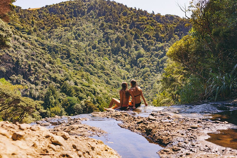 candid, photography, two, female, wearing, bikinis, sitting, waterfalls cliff, front, green
