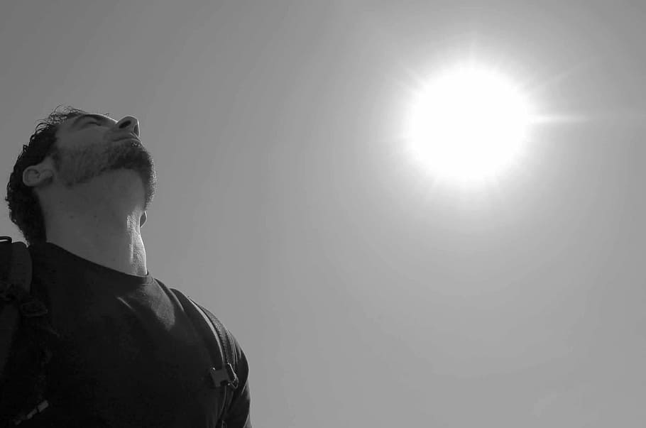 grayscale photo, man, wearing, t-shirt, carrying, backpack, sun, sky, black and white, breathing