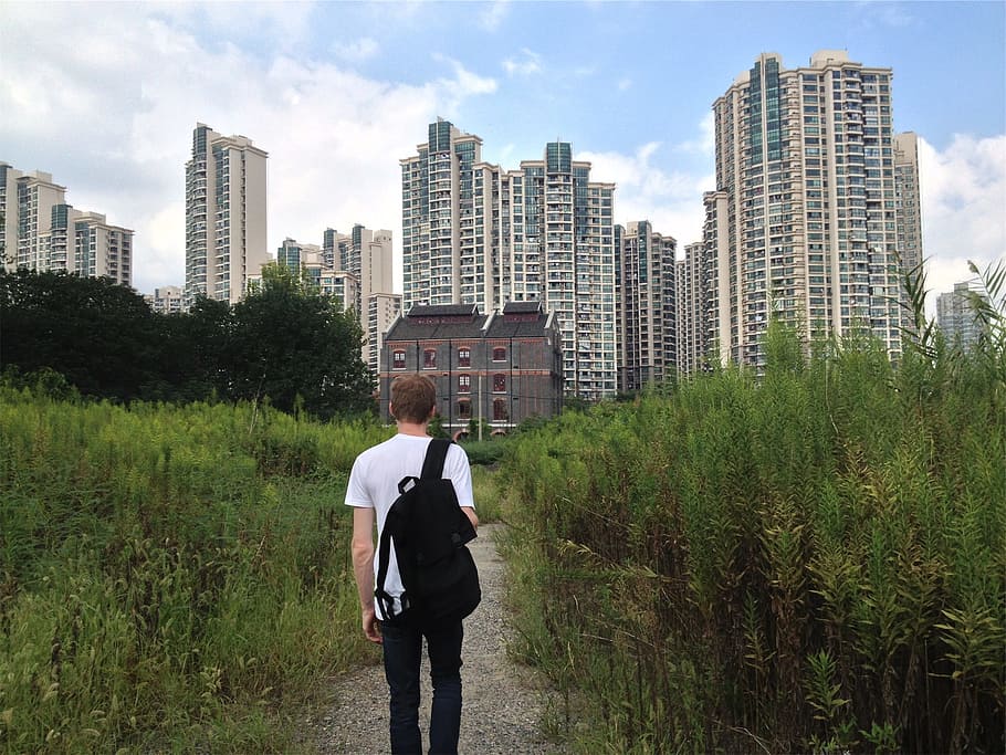 young, guy, student, walking, tshirt, backpack, trail, path, buildings, towers