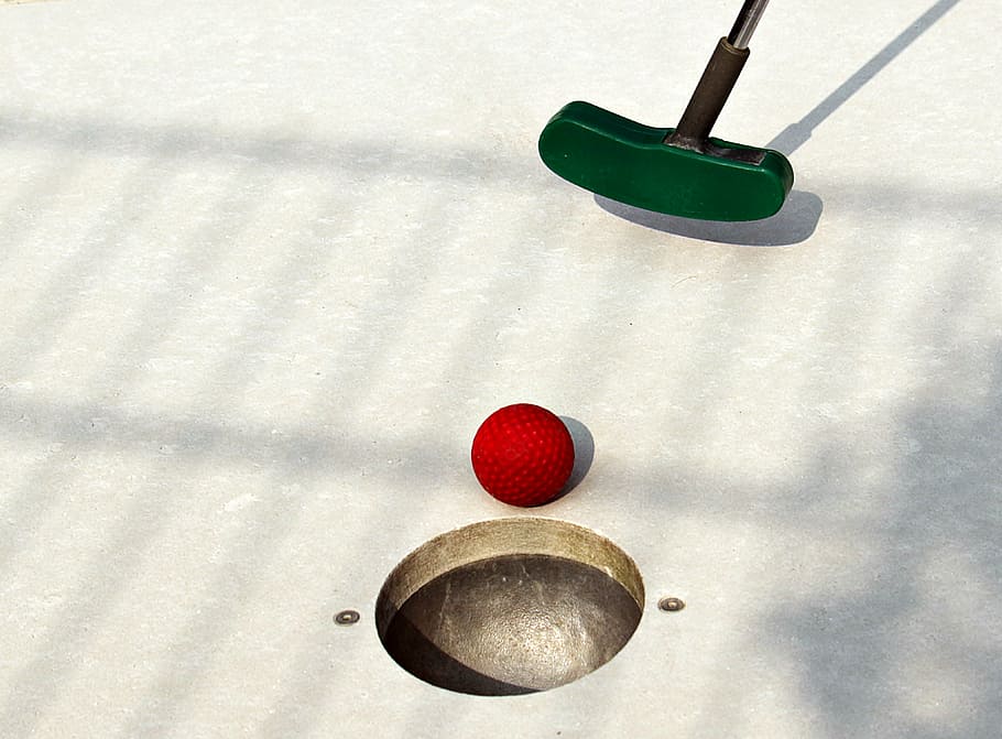 close-up photo, green, golf putter, red, golf ball, hole, miniature golf, mini golf club, skill game, mini golf ball