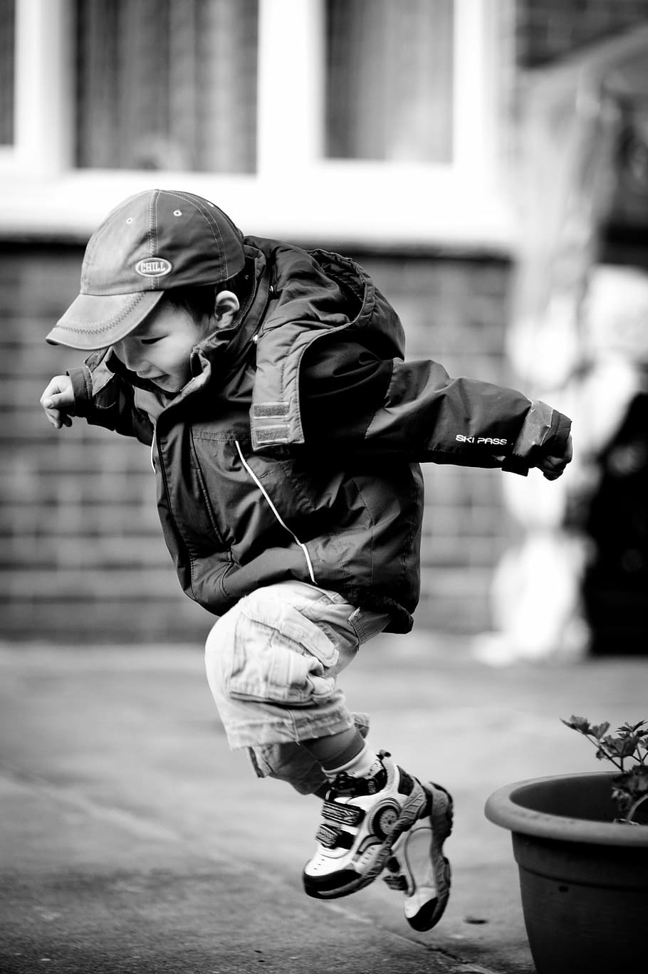 grayscale photo, juming boy, jumping, child, leaping, happy, play, outdoors, black and white, children only