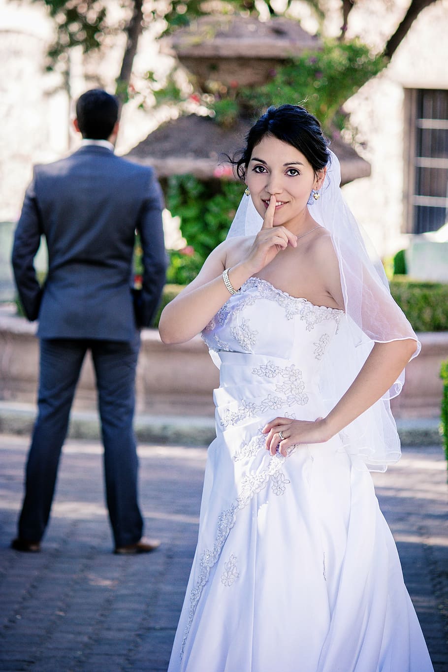 woman, white, strapless wedding gown, showing, silence gesture, sneaky, bride, finger, girl, groom