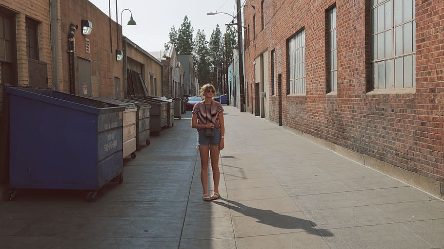 woman, standing, middle, alley, girl, camera, sunglasses, sandles, jean shorts, dumpsters