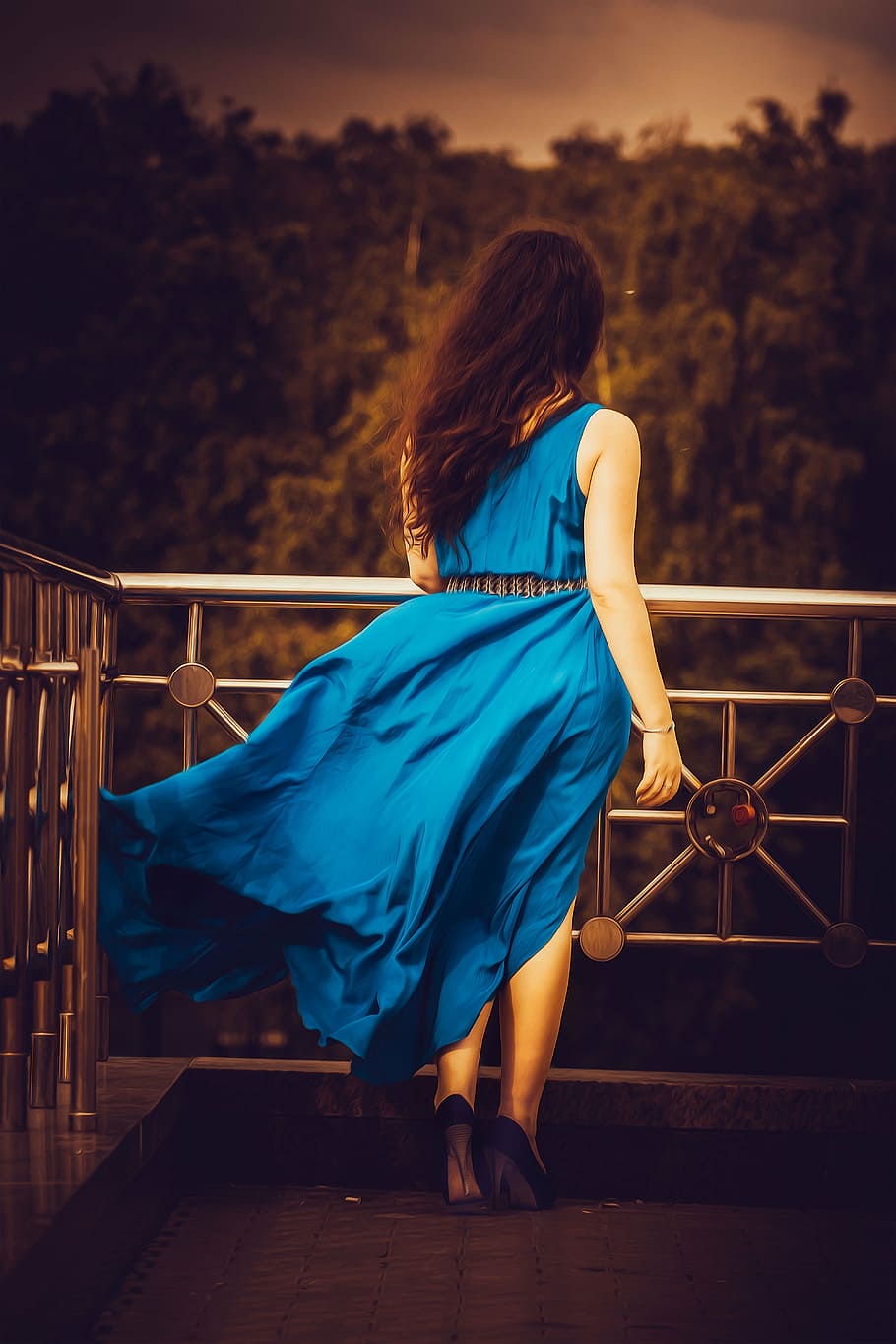 woman, wearing, blue, sleeveless dress, black, heels, standing, gray, metal railings, girl in blue dress