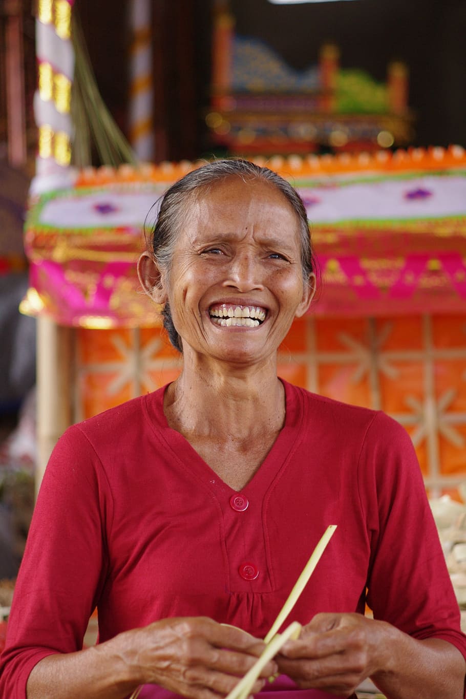 woman, smiling, holding, yellow, string, front, orange, altar, bali, old woman