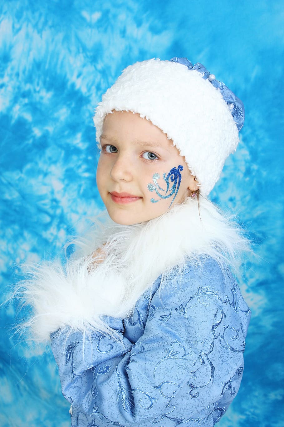 girl, wearing, blue, floral, faux-fur jacket, white, knit, cap, face paint, snow maiden