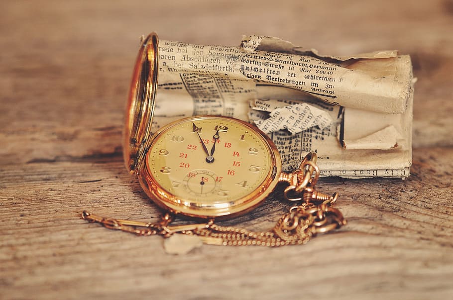 round gold-colored analog pocket, watch, 11:55, clock, clock face, time of, newspaper, rolled, wooden table, old